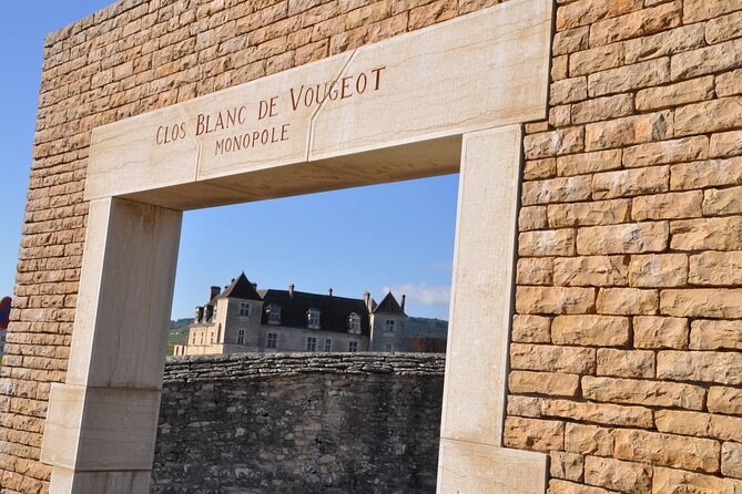A stone gateway cut Clos Blanc de Vougeot, the château's roofs framed inside it