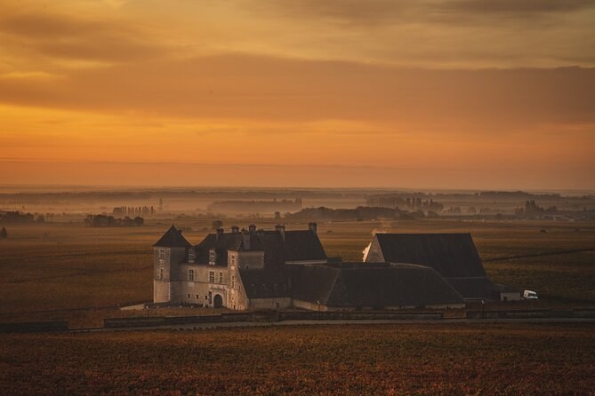 The Clos de Vougeot's château in its vineyard under an orange dawn sky