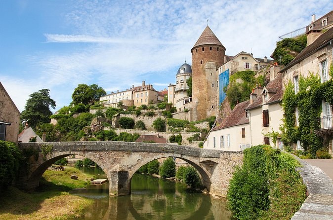 A stone bridge over a river below a town of towers and terraced gardens