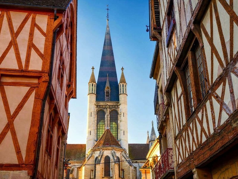 Half-timbered houses framing a church spire patterned in glazed tiles